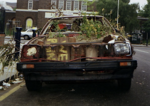 Abandoned car as police statement decorated with weeds and graffiti